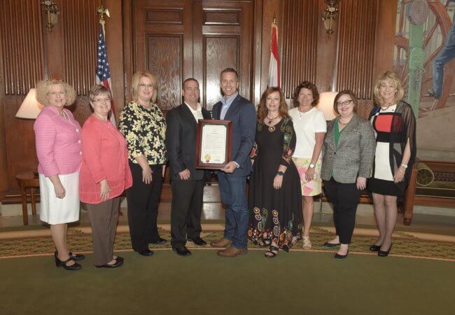 Missouri Governor Eric Greitens holds a proclamation for National Nurses Week surrounded by eight people