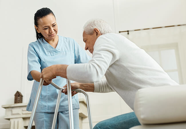 Nurse helping 50+ year old man with using a walker in a home setting