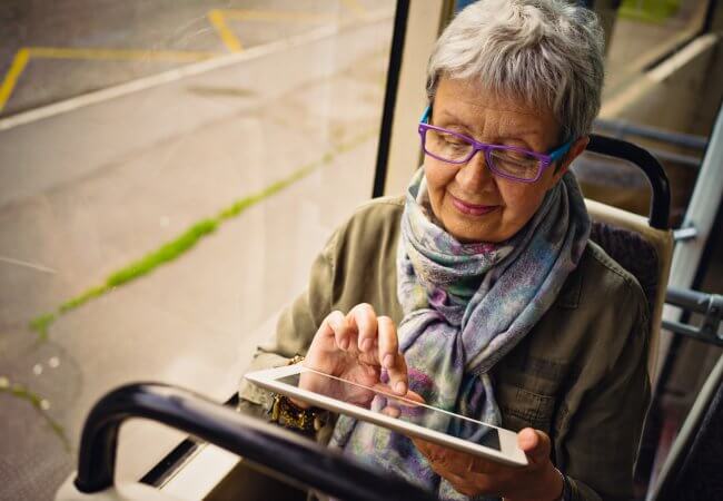 older women read the most-read Campaign for Action blog posts of 2019 using a tablet on a bus