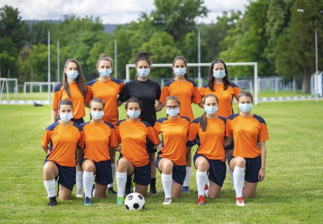 Female college soccer team wearing face masks during coronavirus pandemic.